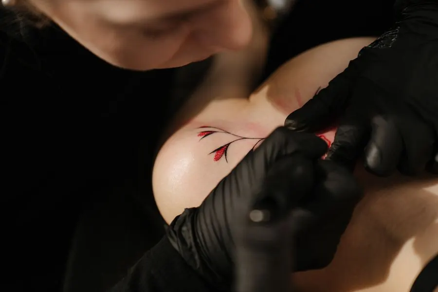 Tatouage floral en cours, la machine suit le contour d'une fleur sur une épaule