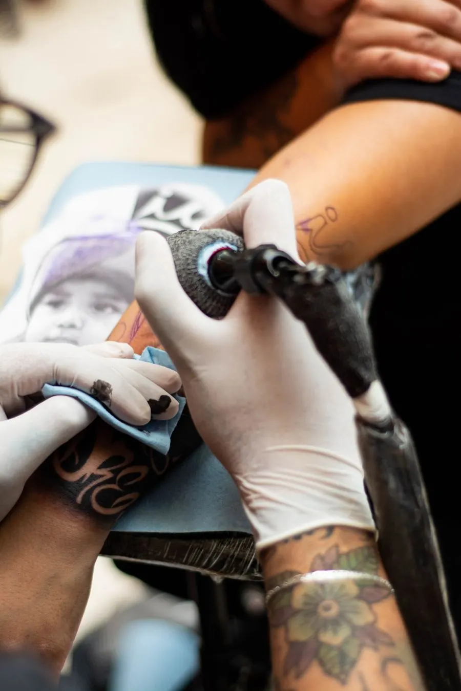 Tatoueuse gantée reproduisant un portrait détaillé d'après un modèle imprimé