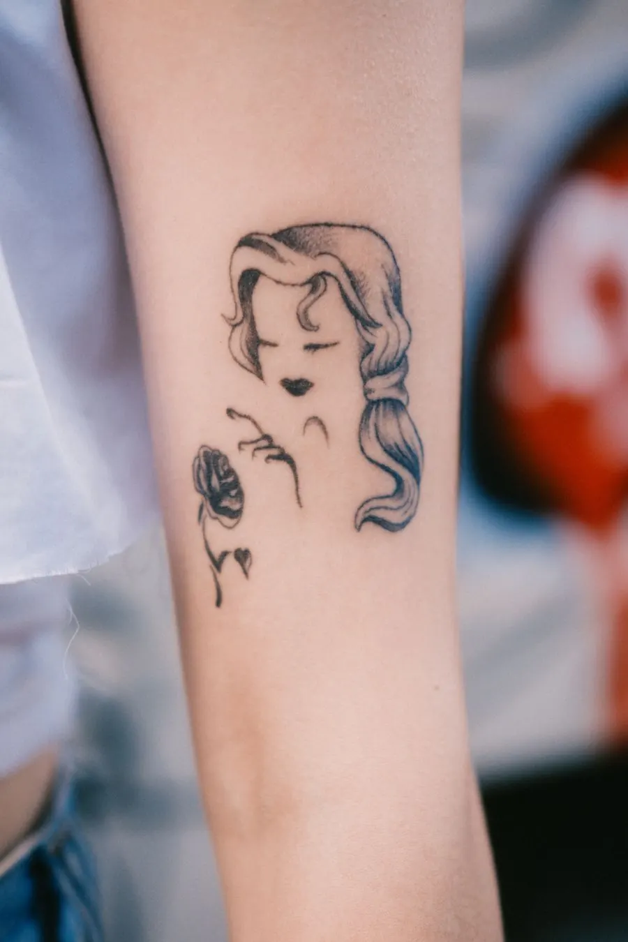 Profil de femme et rose dessinés au trait sur le haut du bras